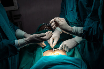Image of surgical team perform surgery operation, nurse hand out sterile scissors to surgeon as...