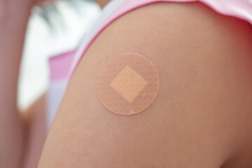Vaccinated little asian girl with adhesive plaster after vaccine injection