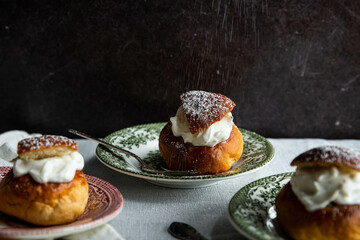 Homemade semlor buns with frangipane and whipped cream on vintage plate.