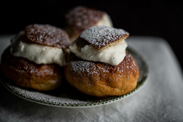Homemade semlor buns with frangipane and whipped cream on vintage plate.