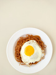 Plate with wholemeal spaghetti pasta, fried egg on the top
and pieces of garlic