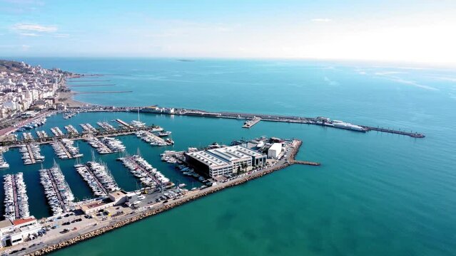 Aerial view of costal city Santa Pola. Situated in southeast of Spain Valencian Community is a famous travel destination. View of beautiful marina of Santa Pola. Baots docked. Drone pan left.