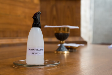 Getting ready for the mass in church. The bottle says "Disinfecting liquid"