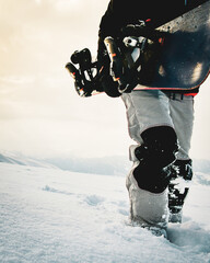 Snowboarder dressed in a full protective gear for extreme freeride snowboarding posing with a snowboard walking. Isolated on gray white snow background.