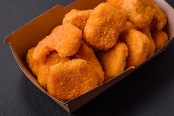 Delicious fresh crispy chicken nuggets on a dark concrete background