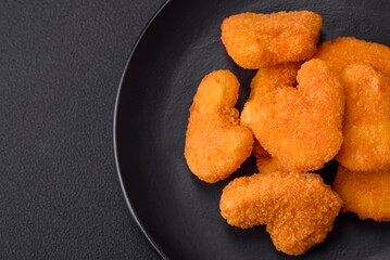 Delicious fresh crispy chicken nuggets on a dark concrete background