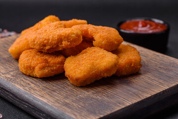 Delicious fresh crispy chicken nuggets on a dark concrete background