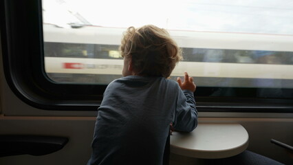 Adorable child traveling by train looking out through window