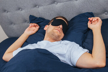 Top view high angle photo of young man wearing sleep mask, happy positive smile, sleep blanket,...