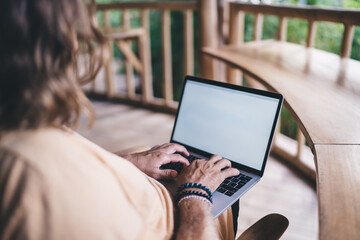 Crop man working on laptop sitting on terrace