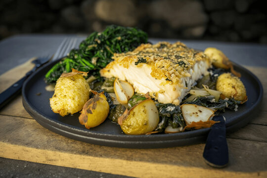 Delicioso prato de bacalhau com broa, acompanhado por grelos e batatas assadas, prato típico português