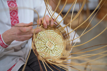 man weaves baskets from willow branches