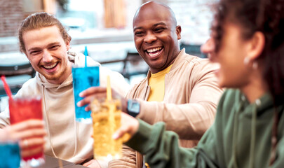 Friends toasting coloured cocktail at bar restaurant - Afro American man having big smile - Trendy life style concept with young people having fun together toasting fancy drinks on happy hour time