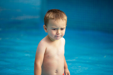 A sad little boy comes out of the pool.