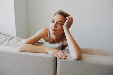 Happy woman smile lying at home on the couch relaxing on a weekend at home with a short haircut hair without filters on a white background, free copy space