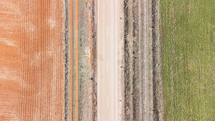 Terreno cultivado en colores de tierra arada naranja y verde atravesado por una carretera 