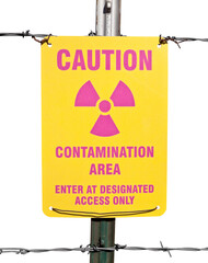 Caution radioactive contamination warning sign on barb wire fence isolated with cut out background.