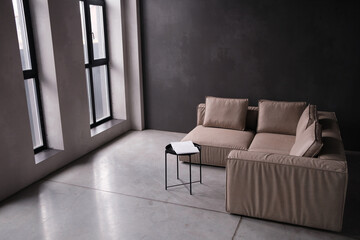 Interior of living room loft style with beige sofa with concrete wall on concrete white floor.