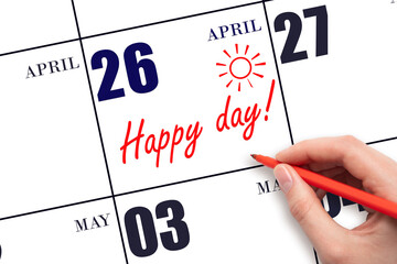 Hand writing the text HAPPY DAY and drawing the sun on the calendar date April 26