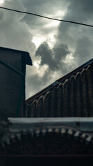 The dark clouds above the roofs are made of slate. Dark clouds between the roofs of houses