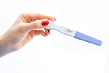 Young woman's hand holding pregnancy test with two stripes on white background. Positive result. Closeup. Point view shot. Empty place for text.