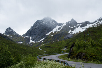 Scenic road along the fjords in Norway. Amazing landscape. Northern nature. Snow-capped mountains. Dramatic clouds. Travel, adventure