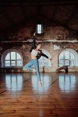 Woman jumping in casual style doing ballet in old studio. Attractive ballerina