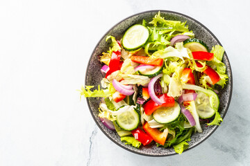 Fototapeta na wymiar Vegan salad with green leaves, cucumber, paprika and tomatoes.