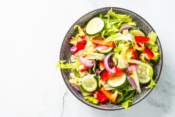 Vegan salad with green leaves, cucumber, paprika and tomatoes.