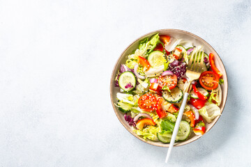 Fresh salad with green leaves, cucumber, paprika and tomatoes.