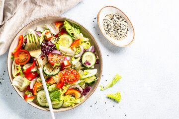 Fresh salad with green leaves, cucumber, paprika and tomatoes.