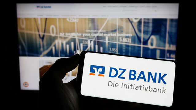 Stuttgart, Germany - 01-29-2023: Person holding mobile phone with logo of German banking company DZ Bank AG on screen in front of business web page. Focus on phone display.