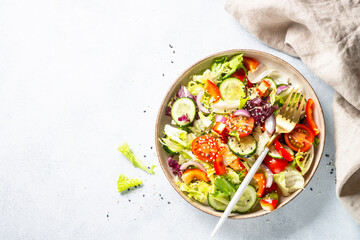 Vegan salad with green leaves, cucumber, paprika and tomatoes.