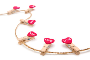 Clothespins decorated with hearts with the inscription LOVE hang on a rope isolated on a white background. Concept for lovers. Valentine's Day holiday. Free space for text.	