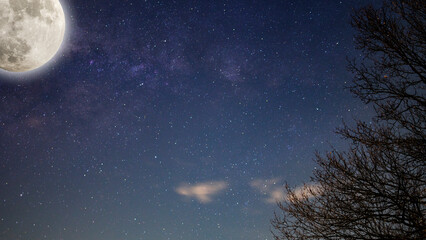 Low light and long exposure photography of the infinite deep space cosmos with bright Moon and flares. Night sky Milky way with full Moon and universe constellations in the background. 