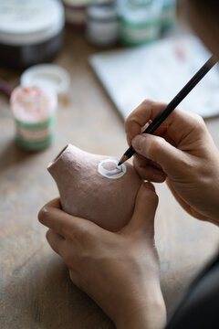 Craftsmaster draws symbol on clay pitcher wanting to decorate kitchen with utensils. Lady master using pencil makes sketch to bring to life and creates new masterpiece for exhibition putting effort