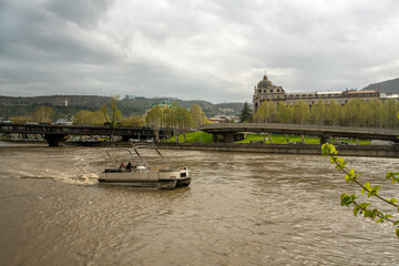 Amazing cityscape with Kura river, statue Mother Georgia and Nikoloz Baratashvili Bridge and boat with two Asien ethnicity people (maybe from Russia) © Marat Lala