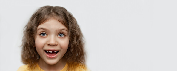 banner portrait of cheerful funny girl without one front top tooth on gray background