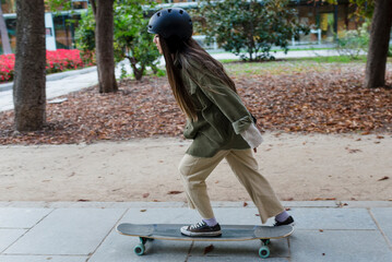 Young skateboarder woman practicing tricks with a longboard outdoors in a park.