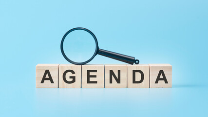 wooden cubes with word Agenda on blue background.