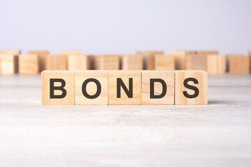 word bonds inscribed on wooden cubes lying on a light table. economy and investments concept.