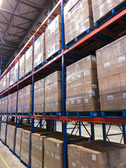 Boxes of wine stacked on pallets in racks of food distribution center.	