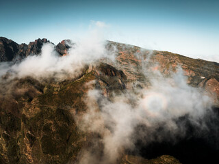 Shot from drone,a shot of pico grande, a landscape bathed in sunlight,majestic mountains under the clouds