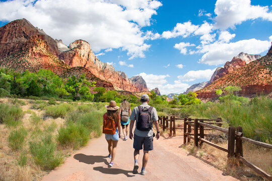 Family Enjoying Summer Mountain Trip. People On Hiking Trip In The Red Mountains Walking On Pathway On Summer Vacation.  Zion National Park, Utah, USA.