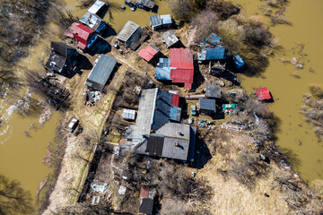 A small farm with wooden houses surrounded by water rising in the spring flood, aerial view