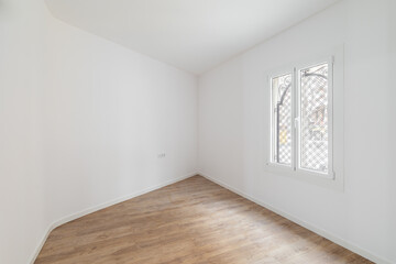 Empty room with laminate flooring, newly painted white walls and bright window. Repair and construction concept.