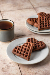 Heart form chocolate waffle cookies in white plate for Valentine's day with tea on pink tileba ckground. Sweet sweets with love. Gift for Valentine's Day