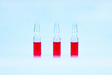 Pharmaceutical ampoules with red medication on blue background