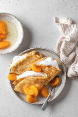 Crepes with fresh mandarin and cream in the filling on white textured background. Maslenitsa or Pancake week traditional concept. Top view, text space, flat lay