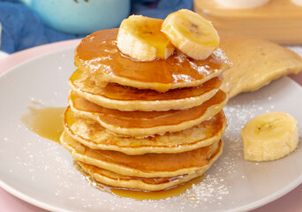classic american breakfast. homemade banana pancakes on plate sprinkled powder and honey. Pancakes on the kitchen table . Pancake slide with honey topping. healthy breakfast. High quality photo